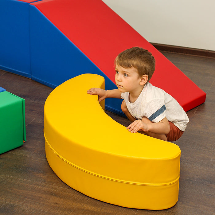 A boy playing with a yellow banana shaped rocking toy#color_yellow