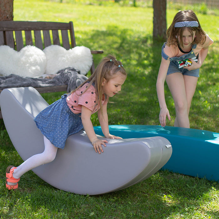 Two girls playing with their banana rocking toys outside in the garden