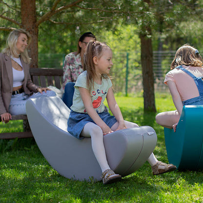 Girl sitting outside on a gray banana shaped foam rocker