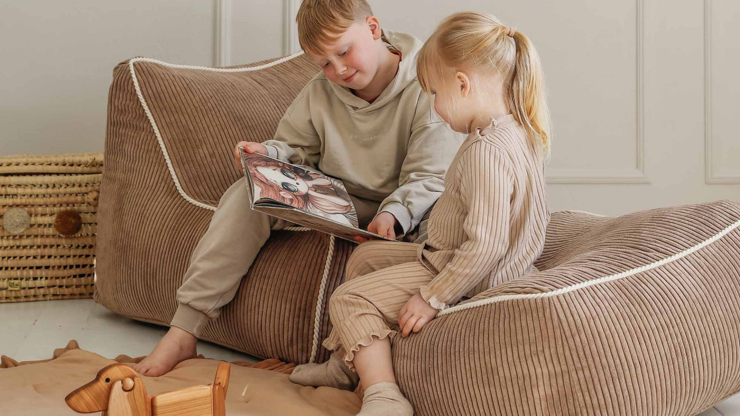 Kinderen lezen een boekje op poef