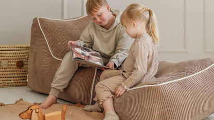 Kinderen lezen een boekje op poef