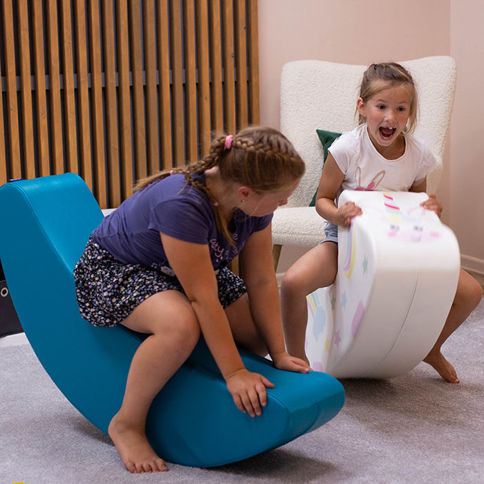 Two girls rocking in a banana shaped rocker toy