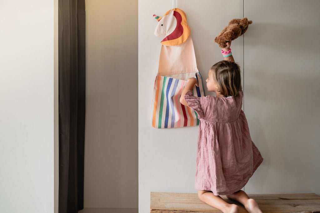 Kind räumt ein Kuscheltier in den Play&Go Toto Unicorn Wandaufbewahrer