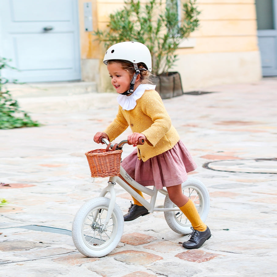 Vintage balance bike beige with wicker basket and crash helmet